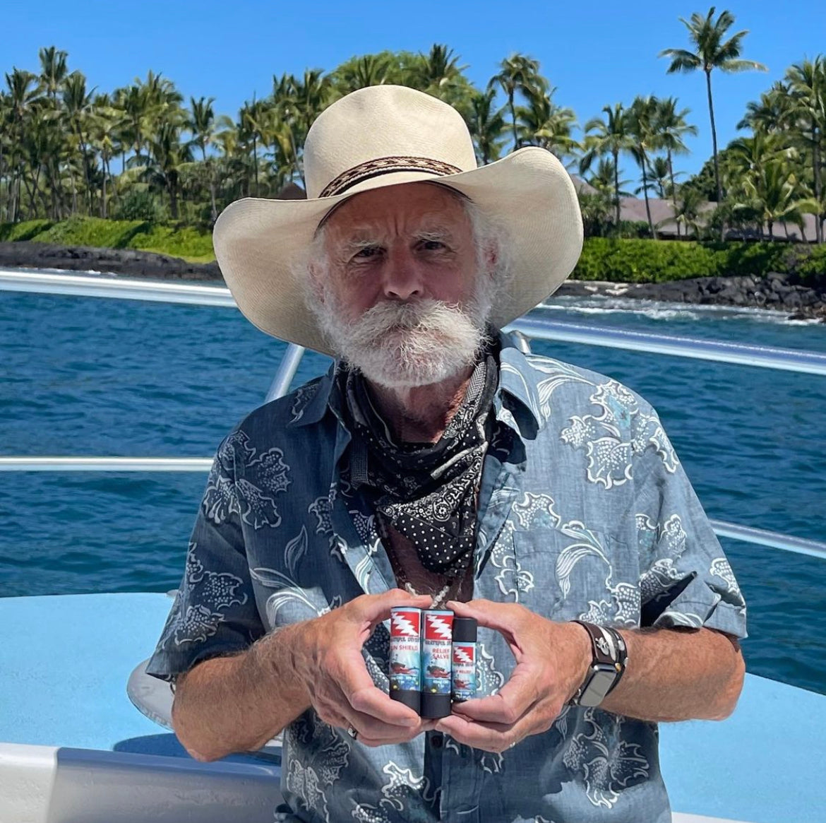 Bob Weir of the Grateful Dead holding Grateful Diver with Heritage Farmed skin care products in front of pool