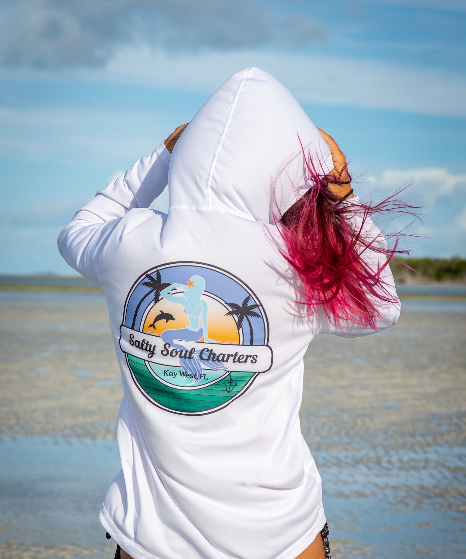 woman with red hair wearing a Grateful Diver Salty Sea Charters Key West UV Shirt Hoodie on sandbar
