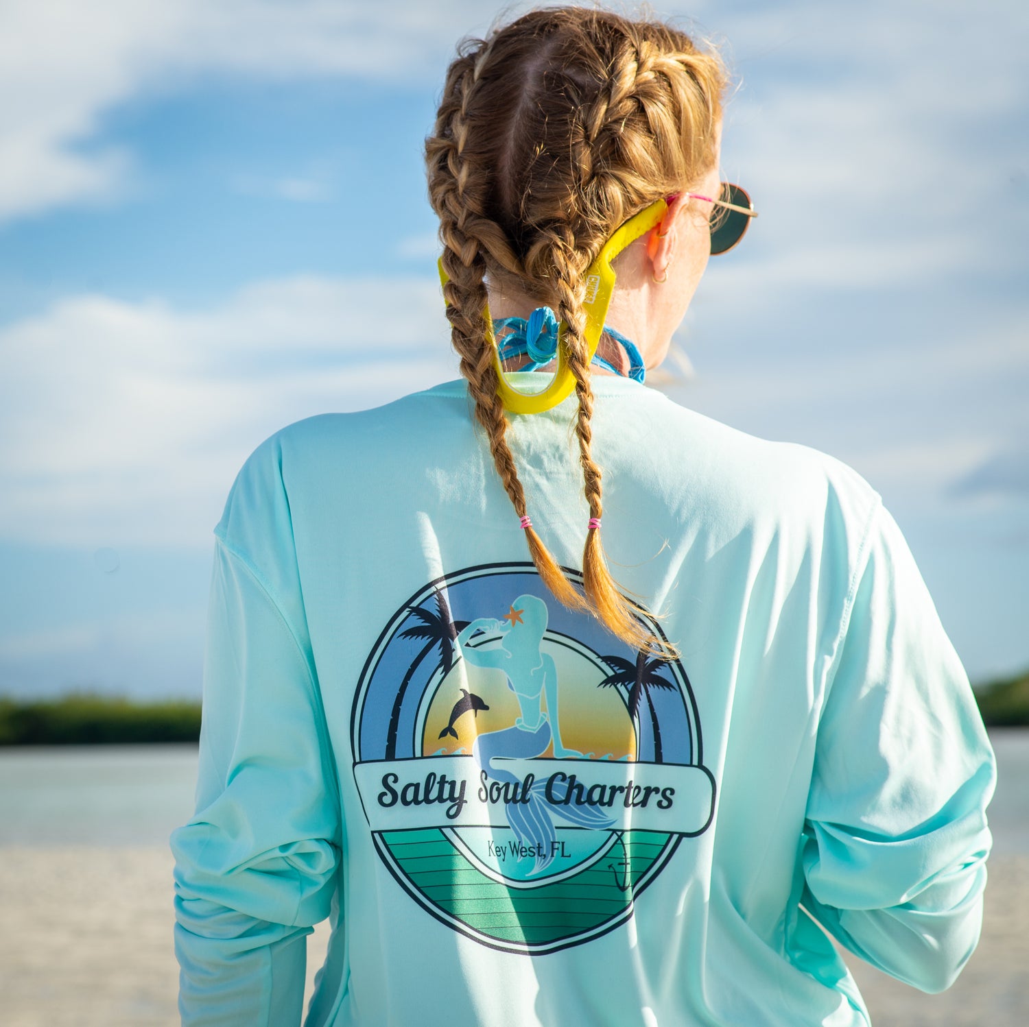 woman in braids wearing a Grateful Diver Salty Sea Charters Key West UV Shirt on sandbar