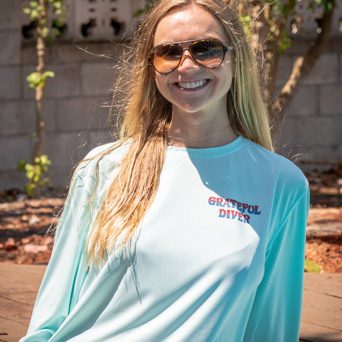 Grateful Diver Sugar Skull UV Shirt in arctic blue on smiling woman showing the front