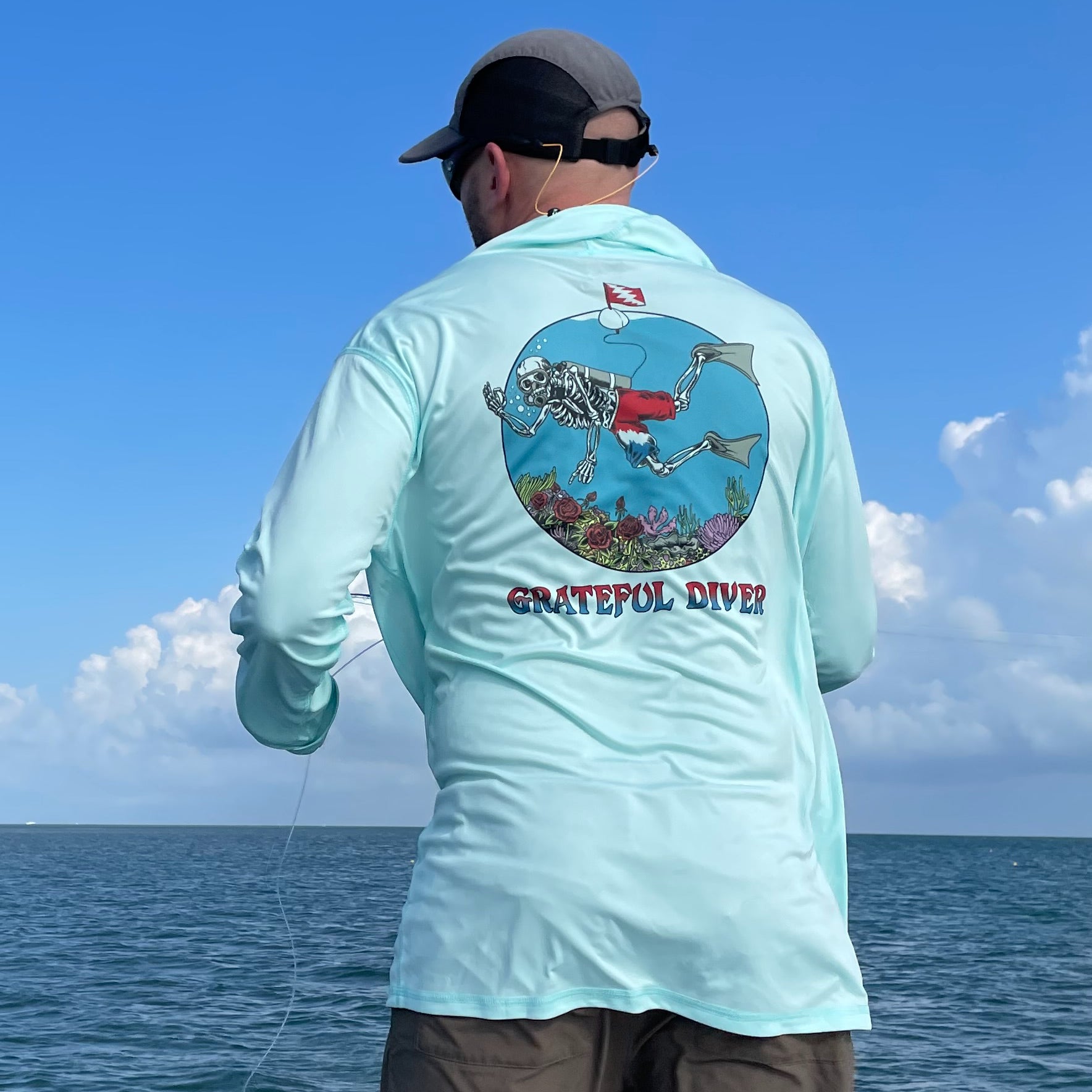 Grateful Diver Skeleton Diver UV Hoodie in seagrass on model showing back in front of ocean