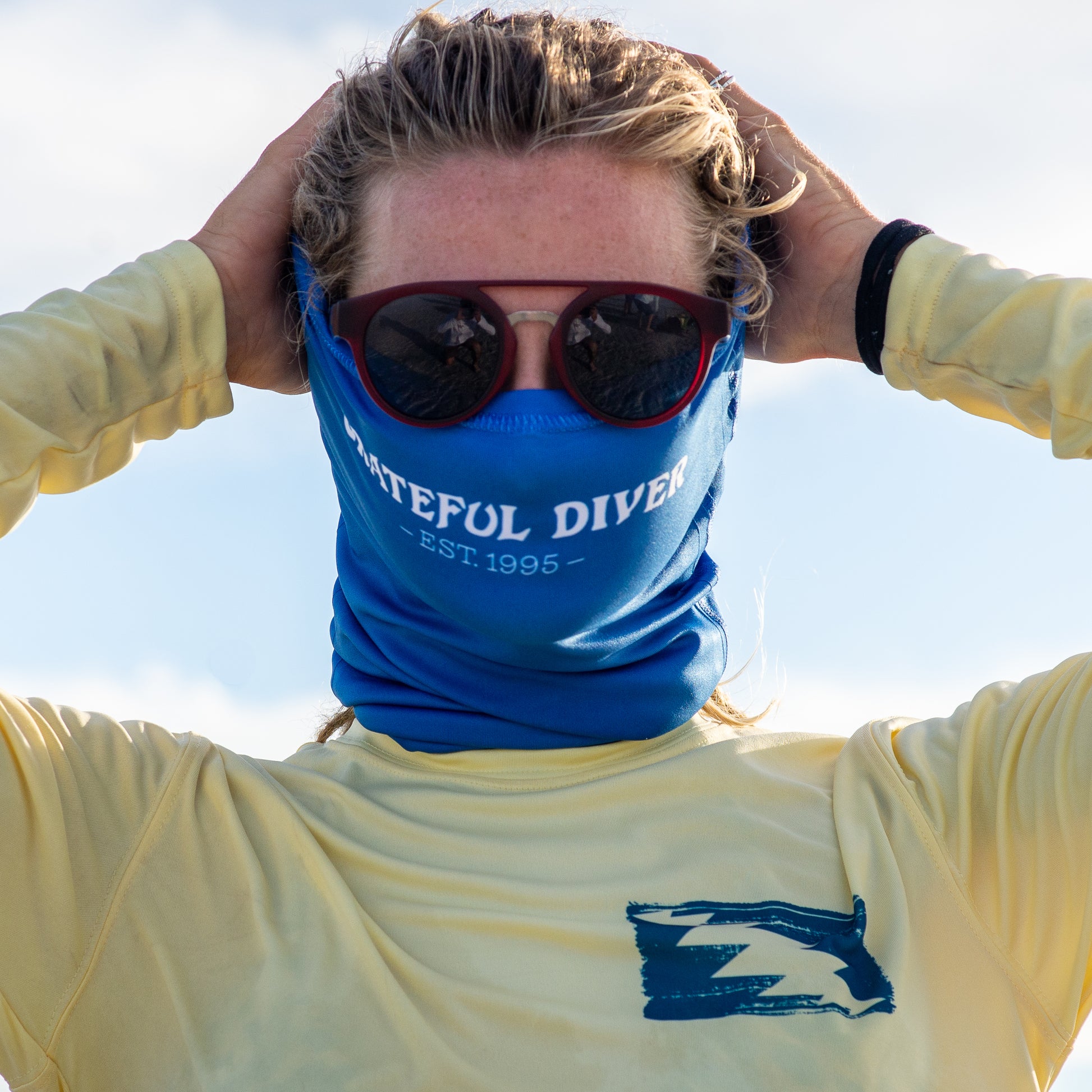 Grateful Diver Classic Dive Flag Neck Gaiter worn as a mask showing front of model's head with sky in the background