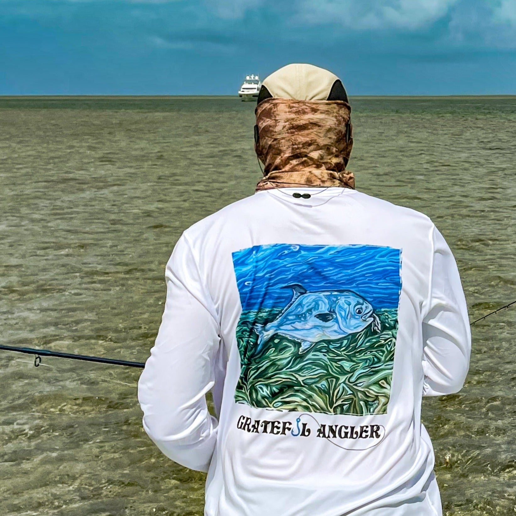 fisher in shallow waters wearing the Grateful Angler Artist's Collection: Catch Your Dreams UV Shirt in white