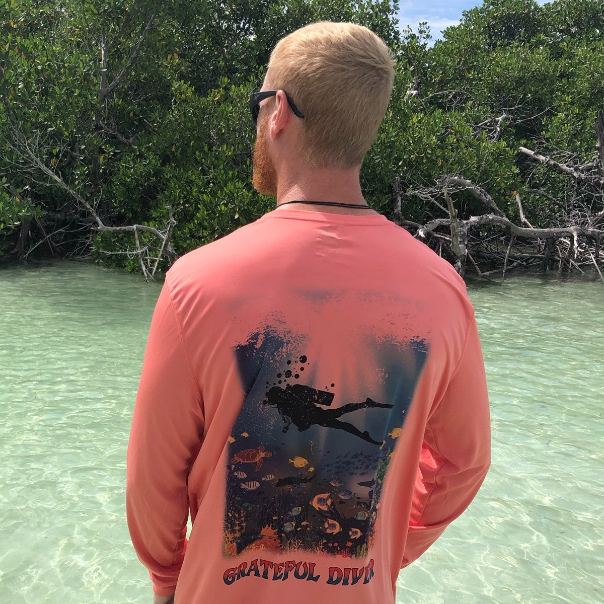 Grateful Diver Reef Diver UV Shirt in salmon on model showing back with mangroves in the background