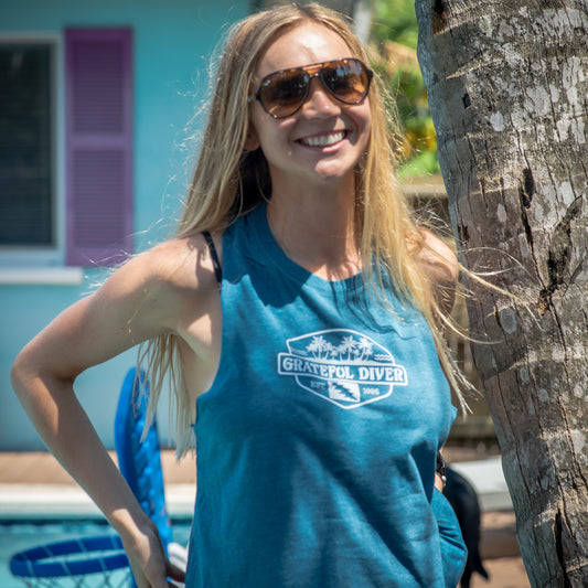 Grateful Diver Palm Tree Racerback Crop Tank Top front on a woman standing by a palm tree in front of a building