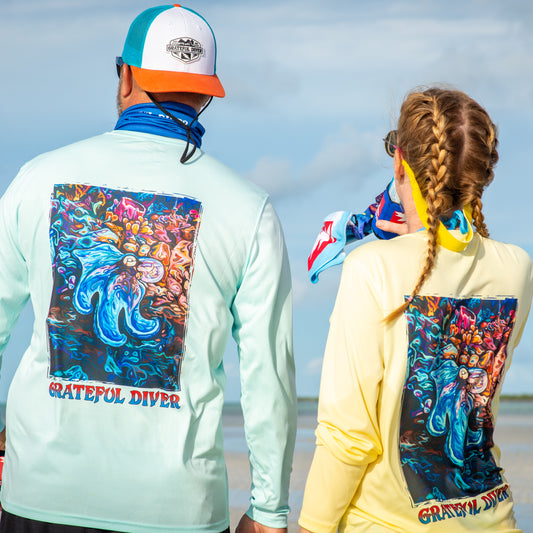 Grateful Diver Artist's Collection by Irina Pushkareva: Caribbean Reef Octopus UV Shirt in arctic blue and pale yellow back shots on two models on sandbar