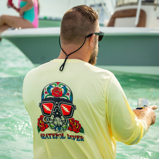 Grateful Diver Sugar Skull UV Shirt in pale yellow on model showing back in front of boat
