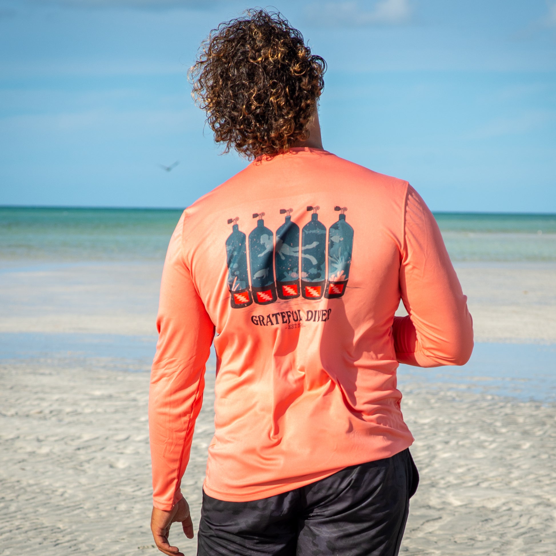Grateful Diver Dive Tanks UV Shirt in salmon on model on sandbar