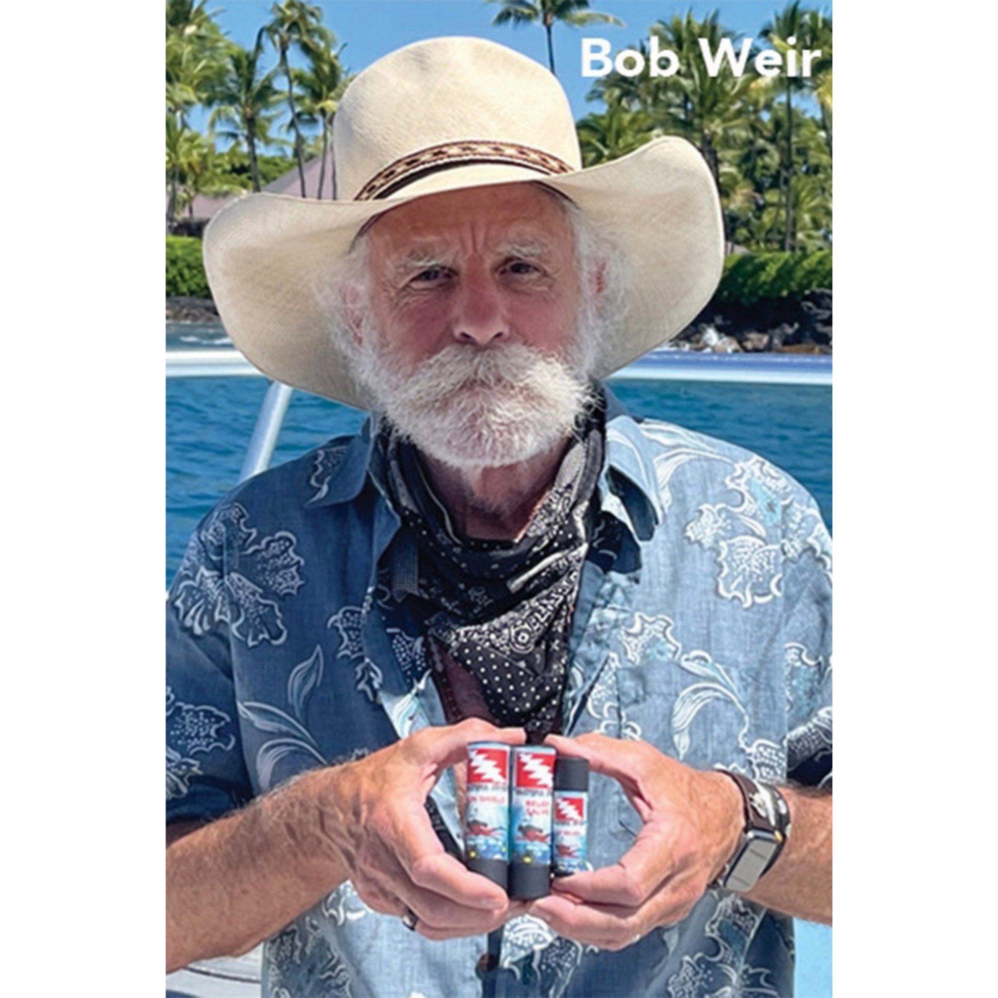 Grateful Diver band member, Bob Weir, holding Grateful Diver skin care products in front of pool
