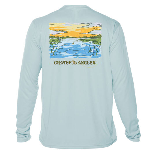 back of arctic blue Grateful Angler Tailing Redfish UV Shirt showing a redfish tail in a stream bed under sunny skies